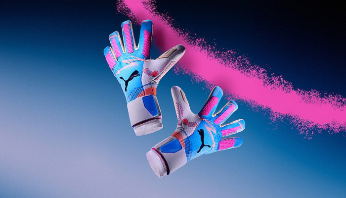 Luva de goleiro Puma Ultra Ultimate Volume Up 2024/25, edição especial com design branco, azul e rosa. Palma de látex de 4mm para máxima aderência, corte híbrido (negativo e rollfinger) para ajuste perfeito, backhand leve e flexível com silicone para maior controle, além de fecho elástico seguro.